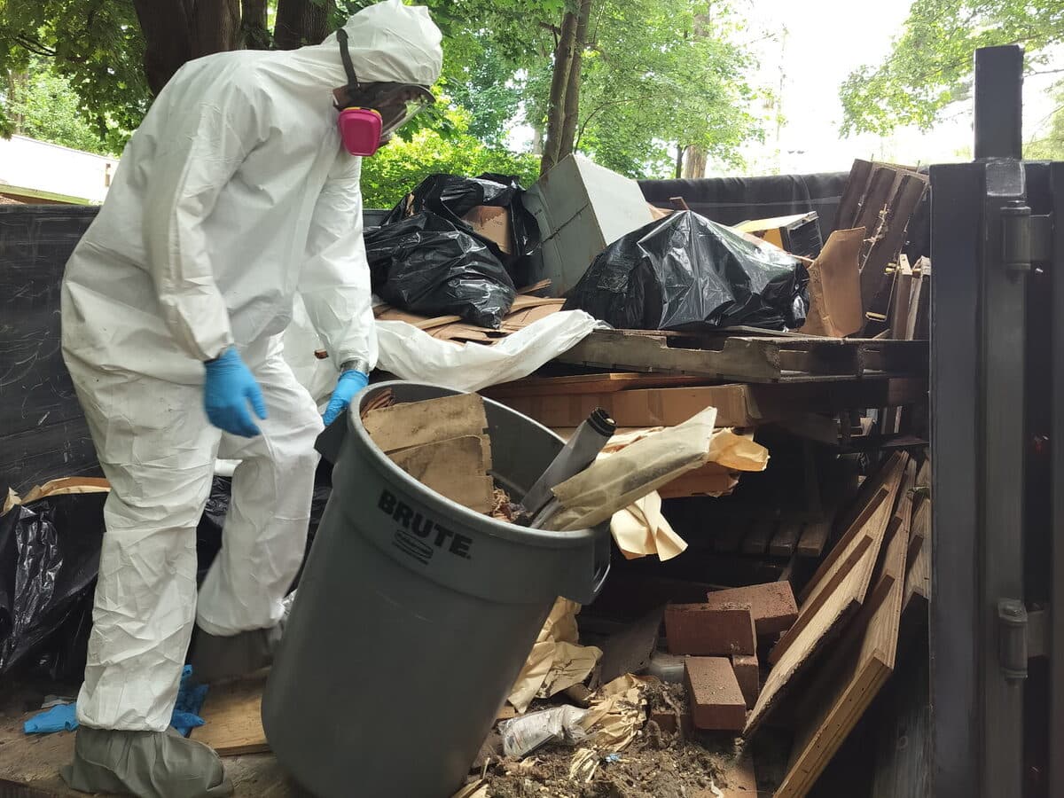 Cleanup worker in protective gear removing debris outdoors