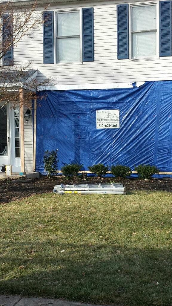 Blue temporary weather barrier securing a house after vehicle impact