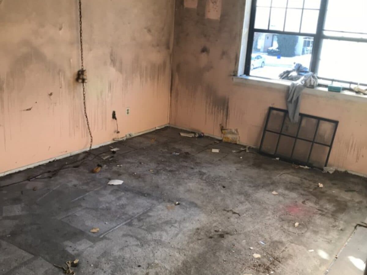 Smoke-stained walls and stripped floor in a fire-damaged room before cleanup