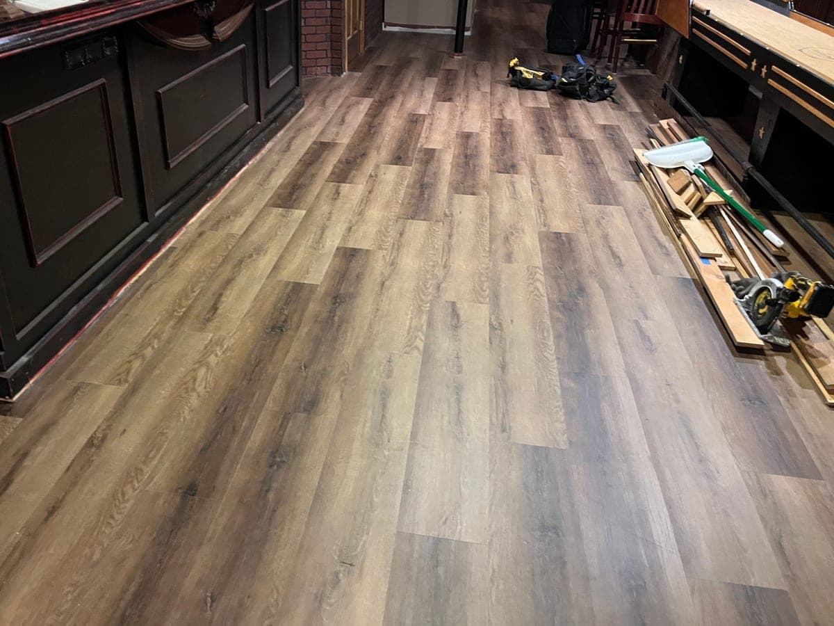 The same basement bar with new wood-look plank flooring installed — after restoration by TRC